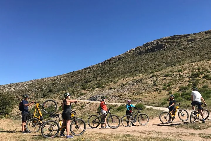 Vététistes debout sur un sentier de terre à flanc de colline au soleil