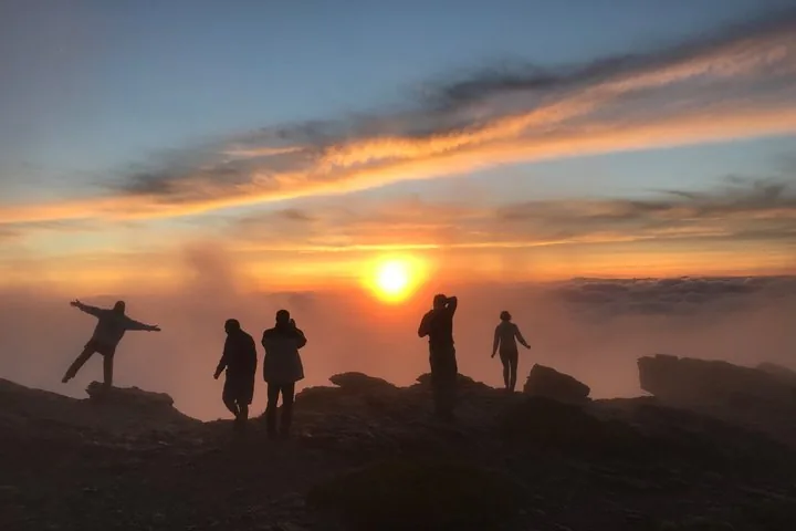 Silhouetten von Menschen, die in der Sierra Nevada einen Sonnenuntergang über den Wolken beobachten